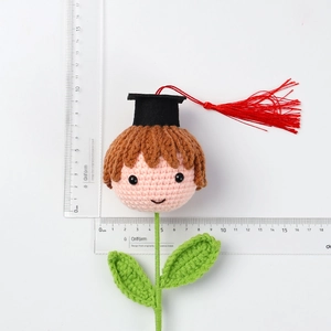 Handmade crochet graduation doll with black cap, red tassel, and green leaves detail