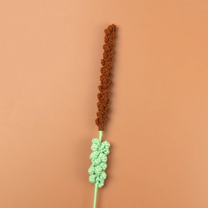Close-up of handmade crochet lavender flower with brown buds and green knitted stem