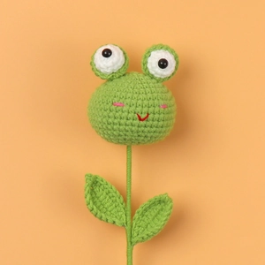 Handmade crochet frog plant flower decoration with green leaves on orange background