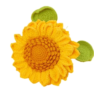 Handmade crochet sunflower with bright yellow petals and green leaves for decoration