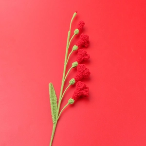 Détail d'un freesia crocheté main avec pétales rouges et tige en fil vert