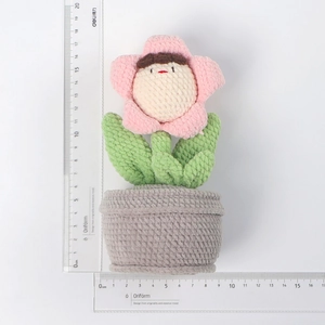 Detaillierte Strickstruktur eines handgehäkelten rosa Blumentopfs mit Linealmaßstab
