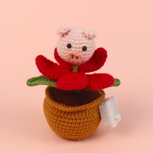 Close-up of handmade crochet pig potted plant with light-up battery box for desk decor
