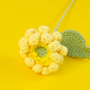 Détail macro d'un gerbera jaune tricoté à la main avec texture en laine et feuille verte