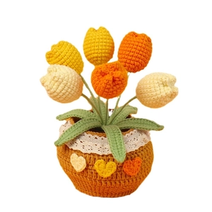 Lebhafte handgefertigte Häkel-Tulpe im Topf mit gelben und orangen Garnblumen als Dekoration.