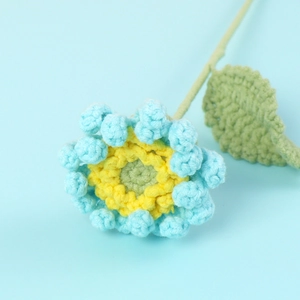 Vue macro d'une fleur de gerbera bleue crochetée à la main en fil doux avec une feuille