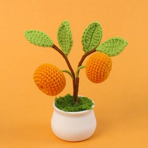Detail of handmade crochet orange potted plant with green leaves in a white ceramic pot