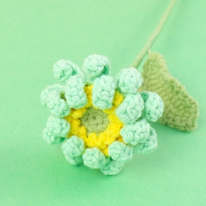 Détail de la texture tricotée de cette fleur de gerbera faite main au crochet vert menthe