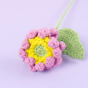 Détail macro d'un gerbera rose fait main au crochet avec texture en fil et feuille verte