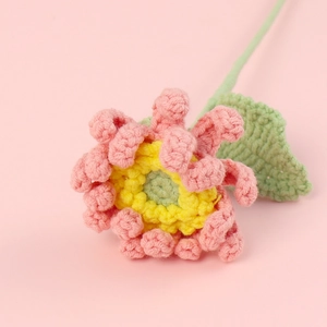 Gros plan d'une gerbera au crochet rose faite main montrant les détails du tricot