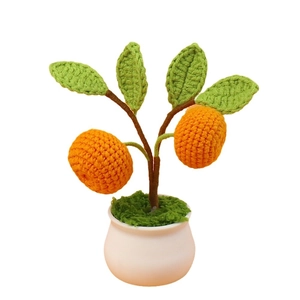 Handmade crochet orange potted plant with green leaves in a white ceramic base