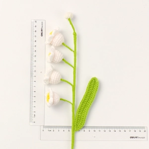 Detail view of handmade crochet lily of the valley showing about 20cm height on white backdrop