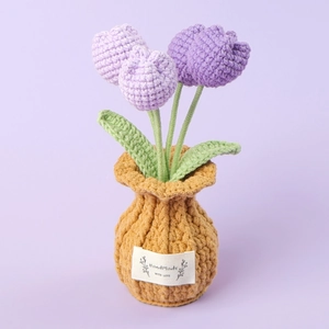 Close-up of handmade knitted purple tulip flowers in a yellow woven pot with a label