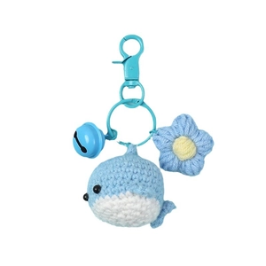 Handmade crochet blue whale keychain with star and bell charm on white background
