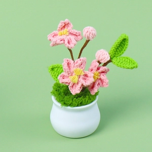 Close-up of handmade crochet cherry blossom bonsai in a white pot with pink flowers