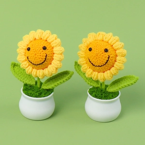 Detail van twee handgehaakte zonnebloem potplanten met schattige lachende gezichten in witte potten