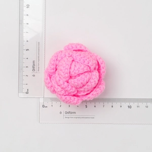 Detail of hand-crocheted pink rose flower with ruler showing 5.5cm size measurement