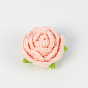 Detailed view of a handmade crochet pink rose head with green leaves for DIY crafts