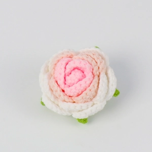 Detailed view of handmade crochet pink and white rose with green leaves accessory