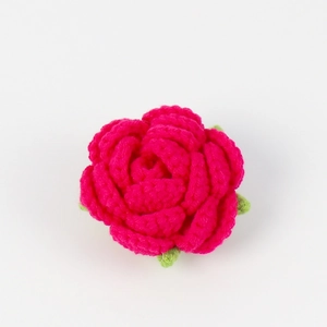 Close-up of handmade crochet rose flower head with realistic knit texture and green leaves