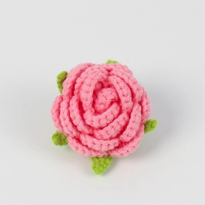 Detail view of handmade crochet pink rose head with green leaves for DIY floral accessories