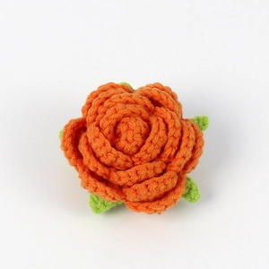 Detailed close-up of handmade crochet rose in orange with green leaves for DIY crafts