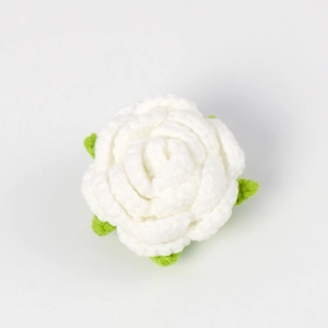 Detailed view of hand-crocheted white rose head with green leaves for DIY bouquet gift