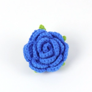 Detail of handcrafted blue crochet rose flower with green leaves and knitted texture