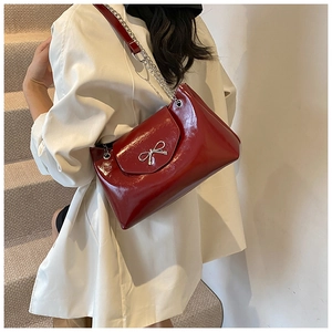 Détail du sac bandoulière en cuir verni bordeaux avec boucle nœud argenté et chaîne