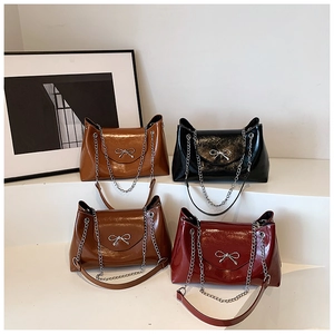Détail de quatre sacs cabas brillants en caramel, marron, noir et rouge avec nœuds argentés