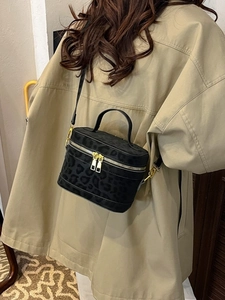 Sac bandoulière noir à motif léopard avec détails dorés porté par un mannequin