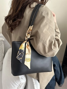 Minimalist black tote bag with white contrast stitching and a patterned silk scarf handle