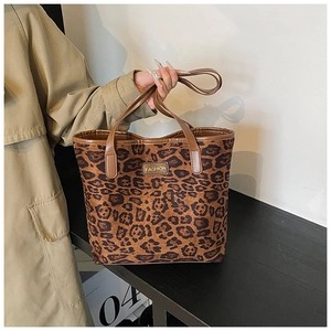Detail of leopard print tote bag featuring a leather strap and FASHION logo tag