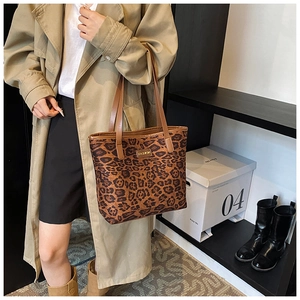 Detail of leopard print tote bag with gold logo plaque on autumn trench coat outfit