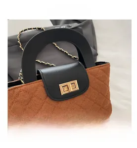 Close-up of quilted fabric texture with gold twist-lock and chain strap on handbag