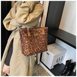 Close-up of leopard print tote bag with brown leather strap worn by a model