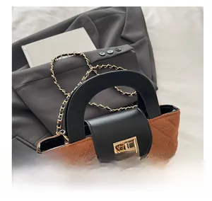 Close-up of quilted handbag with gold twist lock and dual-tone metal chain strap