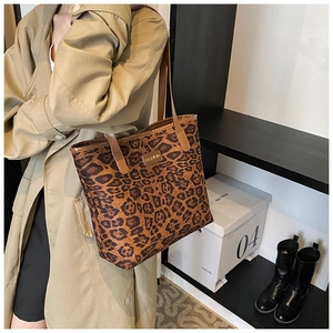 Close-up of leopard print tote bag with gold Fashion emblem on a stylish trench coat