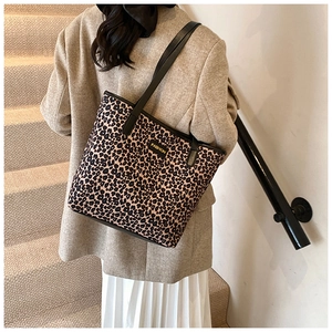 Detail of leopard print tote bag with black leather straps and fashion label decoration
