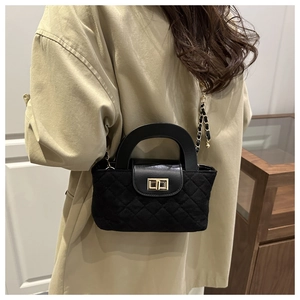 Détail du sac matelassé noir avec fermoir doré sur un trench-coat beige classique