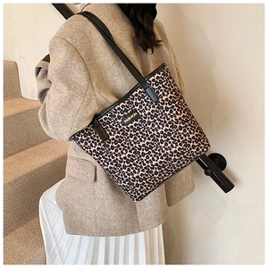 Detailed close-up of leopard print tote bag with black strap and Fashion metal plaque