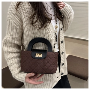 Sac seau matelassé marron avec poignée ronde noire et chaîne dorée sur gilet beige