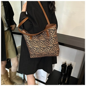 Detail of leopard print tote bag with brown leather straps and fashion label