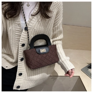 Détail d'un mini sac matelassé marron avec fermoir tournant doré et bandoulière chaîne