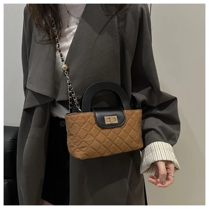 Détail du sac matelassé marron avec rabat en cuir noir et fermoir rotatif doré