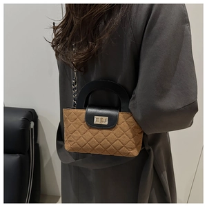 Détail d'un sac à main matelassé marron avec rabat en cuir noir et fermoir doré