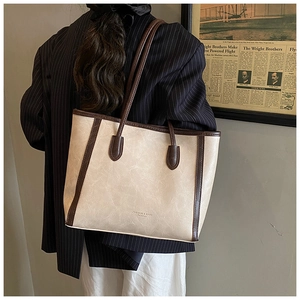 Detail of vintage tote bag with cream leather texture and contrast brown straps