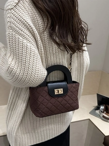 Sac bandoulière marron matelassé avec rabat noir et chaîne dorée porté par un mannequin