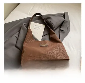 Close-up of brown leopard print hobo shoulder bag with logo plaque on grey blazer