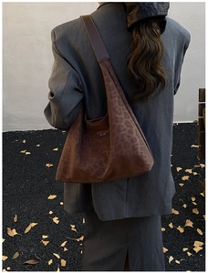 Detail of leopard print hobo bag with metal logo plate on brown textured fabric